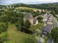 Wieża w Siedlęcinie, otoczona zielenią i stawem, góruje nad okolicą. W tle widać zabudowania i pagórkowaty krajobraz.