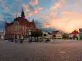 Rynek w Tarnowskich Górach o zachodzie słońca, z ratuszem i kolorowymi kamienicami.