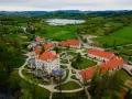 Pałac w Wojanowie otoczony zielenią, z jeziorem w tle. Malowniczy widok z lotu ptaka na zabytkową architekturę i otaczający krajobraz.