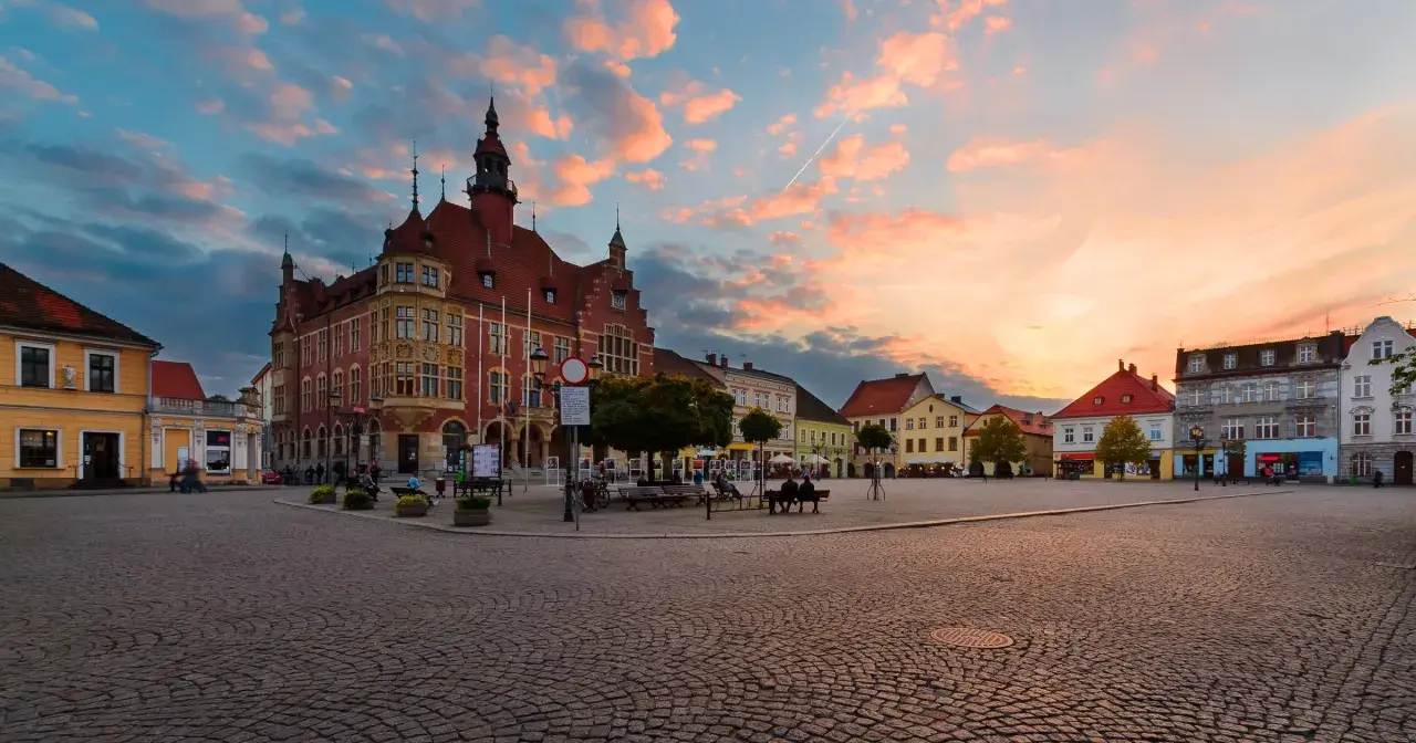 Rynek w Tarnowskich Górach o zachodzie słońca, z ratuszem i kolorowymi kamienicami.