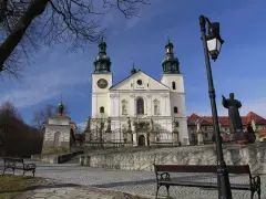 Kalwaria Zebrzydowska zwiedzanie: barokowy kościół z wieżami, kapliczki, ławki i pomnik.