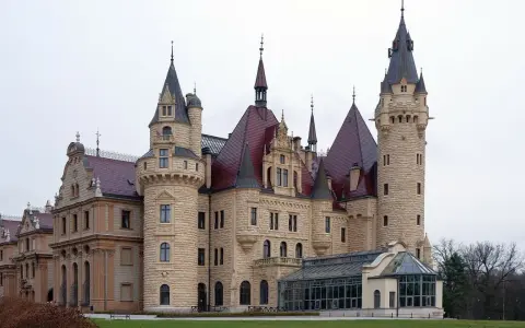 Imponujące pałace w Polsce, jak ten z kamienia i czerwonym dachem, zachwycają wieżami i bogactwem detali architektonicznych.