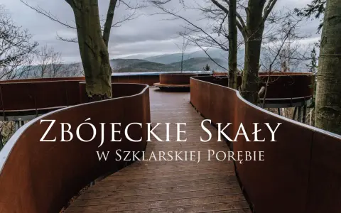 Złoty widok ze ścieżki w koronach drzew w Szklarskiej Porębie. Drewniana kładka z rdzawo-brązowymi balustradami wije się wśród drzew, prowadząc do punktu widokowego.