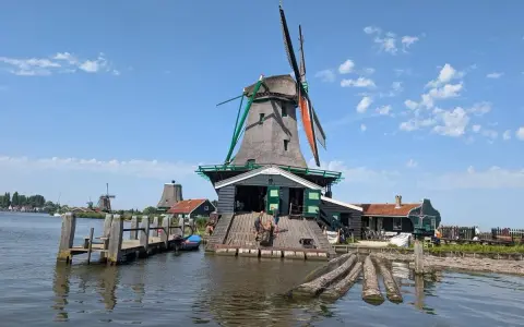 Wiatraki w Zaanse Schans nad wodą, z drewnianym pomostem i łódkami.