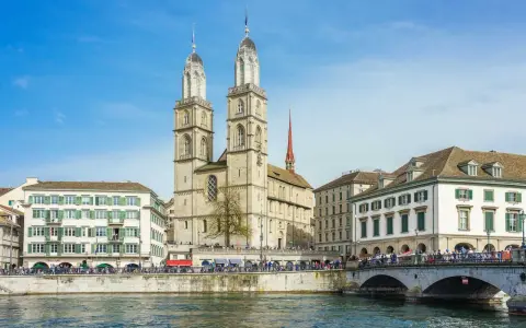 Zurych co warto zobaczyć: imponująca katedra Grossmünster z dwiema wieżami, rzeka Limmat i most.