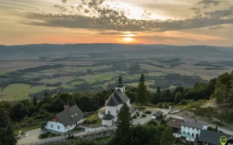 Zachód słońca nad malowniczym krajobrazem z bazyliką Matki Bożej Śnieżnej na wzgórzu.