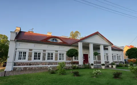 Elegancki pałac w Korczewie z kolumnowym portykiem i kamienną podmurówką, otoczony zadbanym ogrodem.