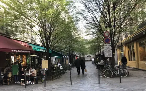 Spacerem w le Marais, Paryż, z kawiarniami i ludźmi spacerującymi pod drzewami.