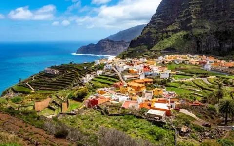 Kolorowa wioska na zboczu góry, tarasowe pola i ocean. To jedne z wielu **la gomera atrakcje**, które zachwycają.