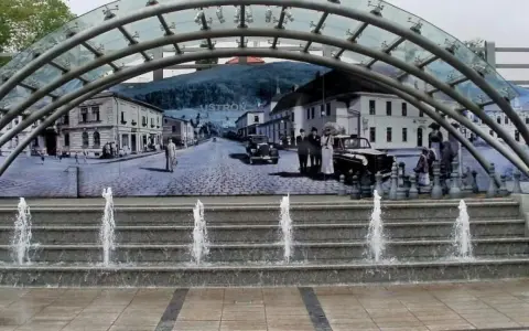 Ustroń rynek: fontanna i mural przedstawiający historyczne miasto z ludźmi w strojach z epoki i zabytkowymi samochodami.