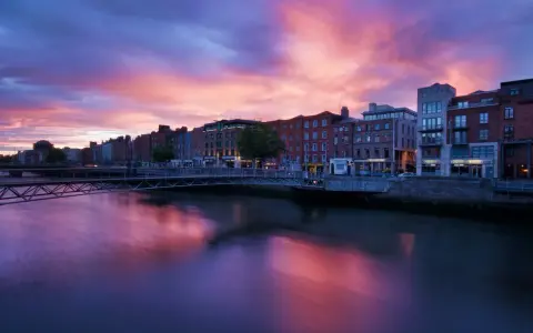 Zachód słońca nad rzeką Liffey w Dublinie. Widok na most i zabytkowe kamienice, idealne miejsce, by zobaczyć Dublin.