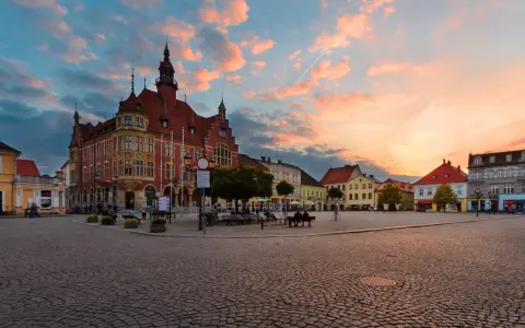 Rynek w Tarnowskich Górach o zachodzie słońca, z ratuszem i kolorowymi kamienicami.