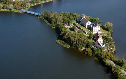 Ełk: zamek krzyżacki na wyspie, idealne miejsce na zwiedzanie. Most prowadzi do historycznych budynków otoczonych zielenią i wodą.
