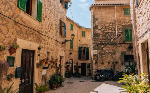 Urokliwa uliczka w Valldemossa. Zobacz kamienne domy z zielonymi okiennicami i mnóstwo kwiatów. Idealne miejsce na spacer i odkrywanie uroków miasteczka.