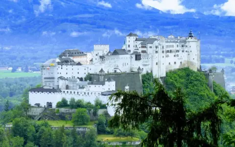 Majestatyczna twierdza Hohensalzburg, obowiązkowy punkt na liście "Salzburg co zobaczyć", góruje nad zielonymi wzgórzami i miastem.
