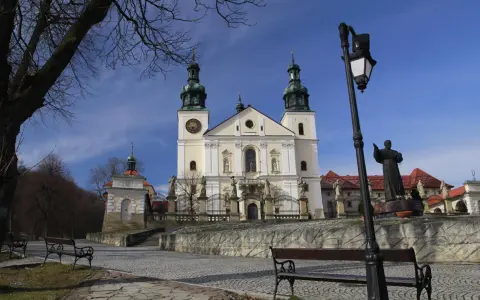Kalwaria Zebrzydowska zwiedzanie: barokowy kościół z wieżami, kapliczki, ławki i pomnik.