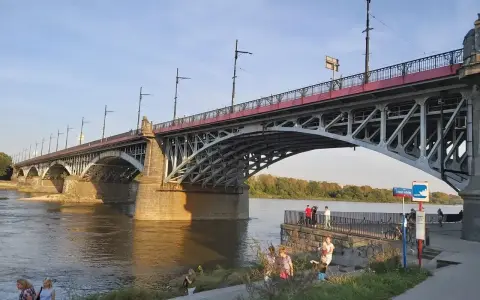 Most Poniatowskiego nad Wisłą, z ludźmi spacerującymi po bulwarach i podziwiającymi architekturę.