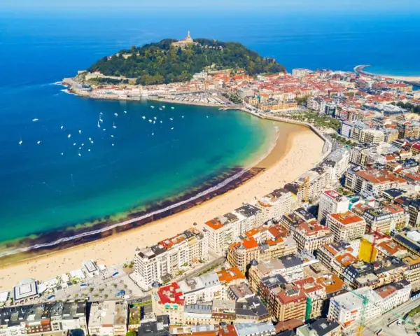 Widok z lotu ptaka na zatokę La Concha w San Sebastian, z piaszczystą plażą, turkusową wodą i zabudową miejską.