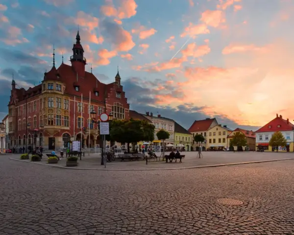 Rynek w Tarnowskich Górach o zachodzie słońca, z ratuszem i kolorowymi kamienicami.