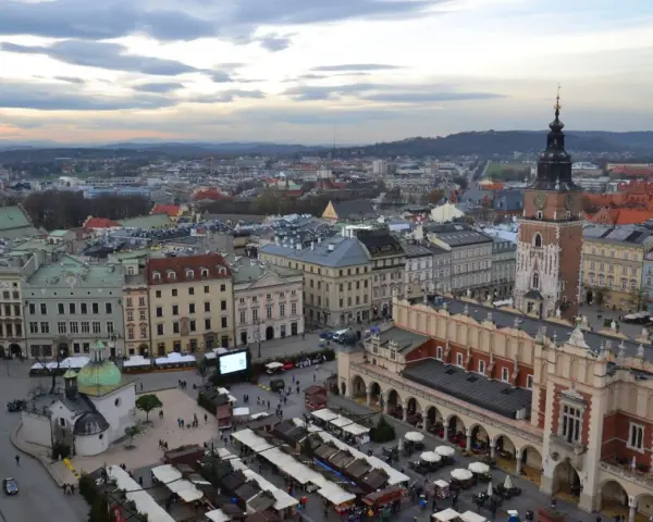 Widok na Rynek Główny w Krakowie z dominującą wieżą Mariacką. W dole kramy jarmarku, Sukiennice i kościółek.