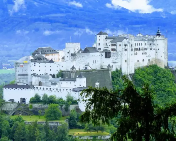 Majestatyczna twierdza Hohensalzburg, obowiązkowy punkt na liście "Salzburg co zobaczyć", góruje nad zielonymi wzgórzami i miastem.