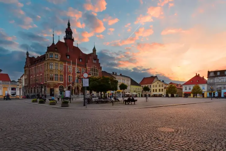 Rynek w Tarnowskich Górach o zachodzie słońca, z ratuszem i kolorowymi kamienicami.