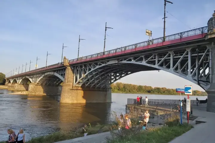 Most Poniatowskiego nad Wisłą, z ludźmi spacerującymi po bulwarach i podziwiającymi architekturę.