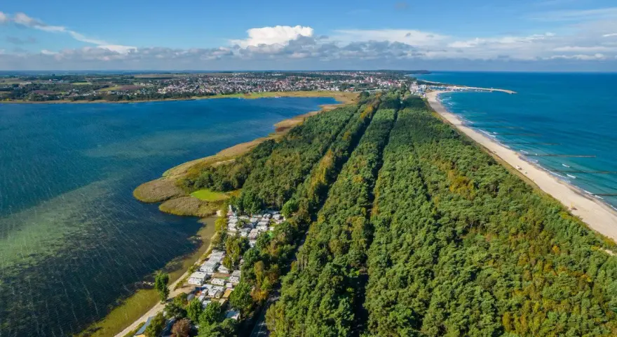 Półwysep Helski widziany z lotu ptaka: las sosnowy, plaża, morze i zatoka. Widać też miasteczko i kemping.