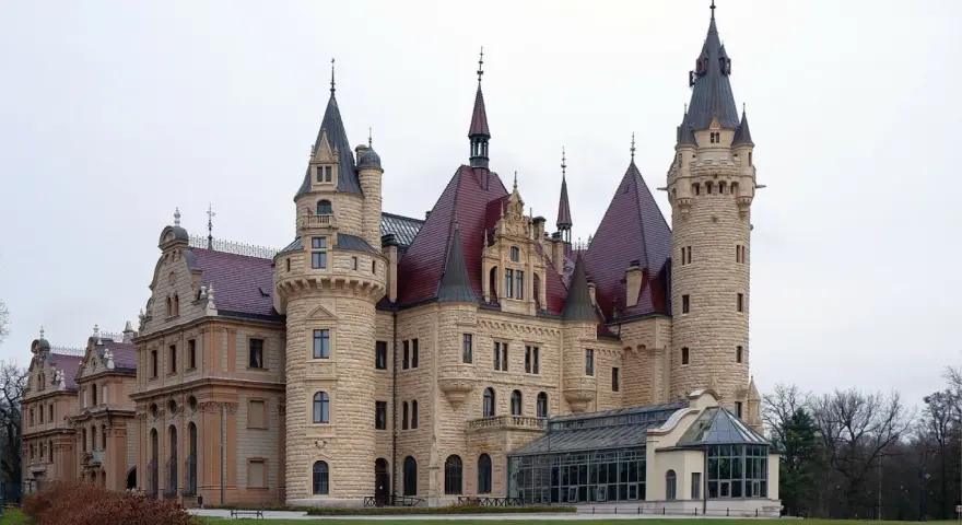 Imponujące pałace w Polsce, jak ten z kamienia i czerwonym dachem, zachwycają wieżami i bogactwem detali architektonicznych.