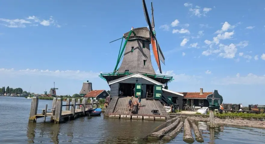 Wiatraki w Zaanse Schans nad wodą, z drewnianym pomostem i łódkami.