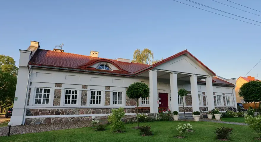 Elegancki pałac w Korczewie z kolumnowym portykiem i kamienną podmurówką, otoczony zadbanym ogrodem.