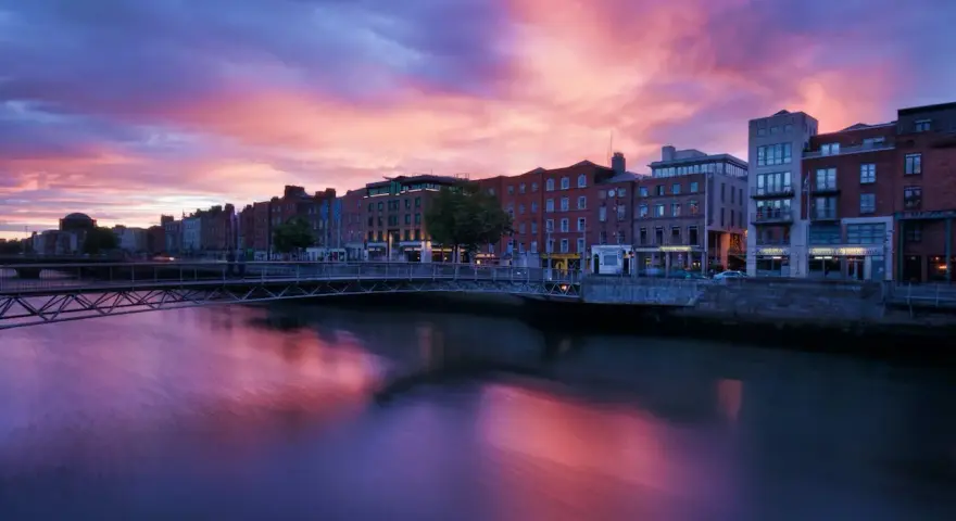 Zachód słońca nad rzeką Liffey w Dublinie. Widok na most i zabytkowe kamienice, idealne miejsce, by zobaczyć Dublin.