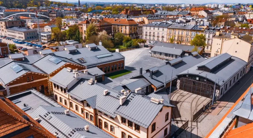 Widok z lotu ptaka na teren Muzeum Motoryzacji Kraków, z zabytkowymi budynkami i torami kolejowymi.