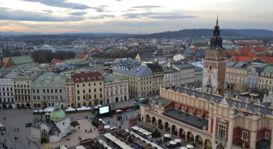 Widok na Rynek Główny w Krakowie z dominującą wieżą Mariacką. W dole kramy jarmarku, Sukiennice i kościółek.