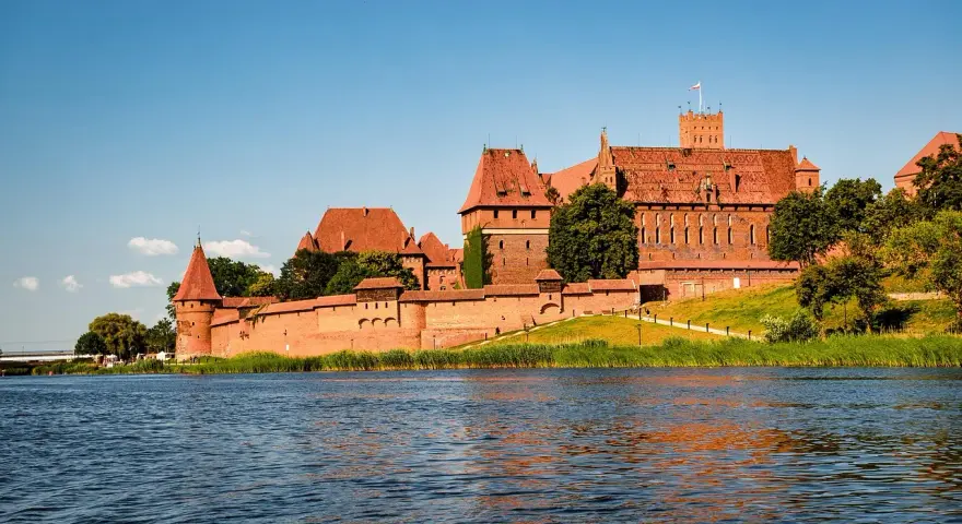 Potężny zamek w Malborku nad rzeką. Zwiedzanie zamku w Malborku to podróż w czasie.