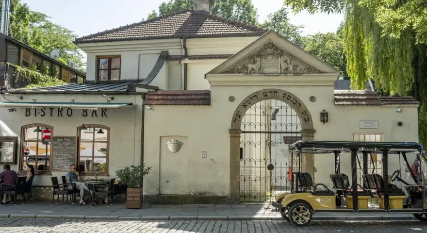 Bistro Bar obok bramy z hebrajskimi napisami, charakterystycznej dla krakowskiej dzielnicy żydowskiej. Obok stoi żółty meleks.