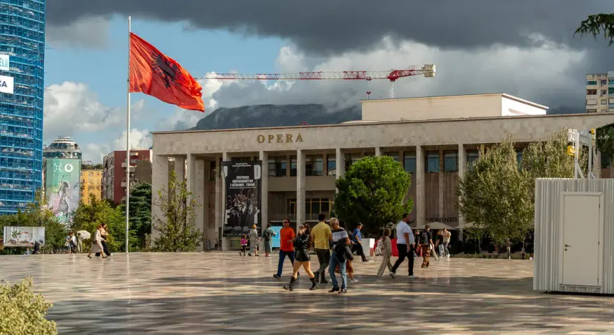 Plac przed Operą w Tiranie, z albańską flagą. Warto zobaczyć to miejsce, spacerując po centrum.