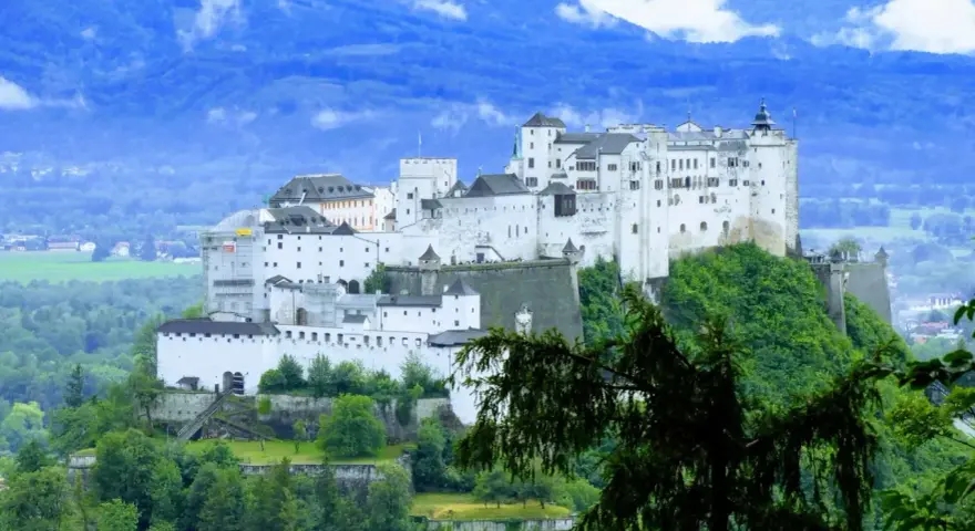 Majestatyczna twierdza Hohensalzburg, obowiązkowy punkt na liście "Salzburg co zobaczyć", góruje nad zielonymi wzgórzami i miastem.