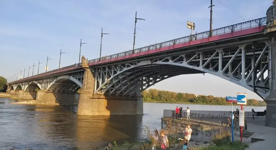 Most Poniatowskiego nad Wisłą, z ludźmi spacerującymi po bulwarach i podziwiającymi architekturę.