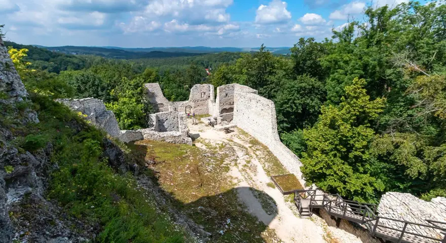 Ruiny zamku Pilcza w Smoleniu, otoczone bujną zielenią, z widokiem na malownicze wzgórza.