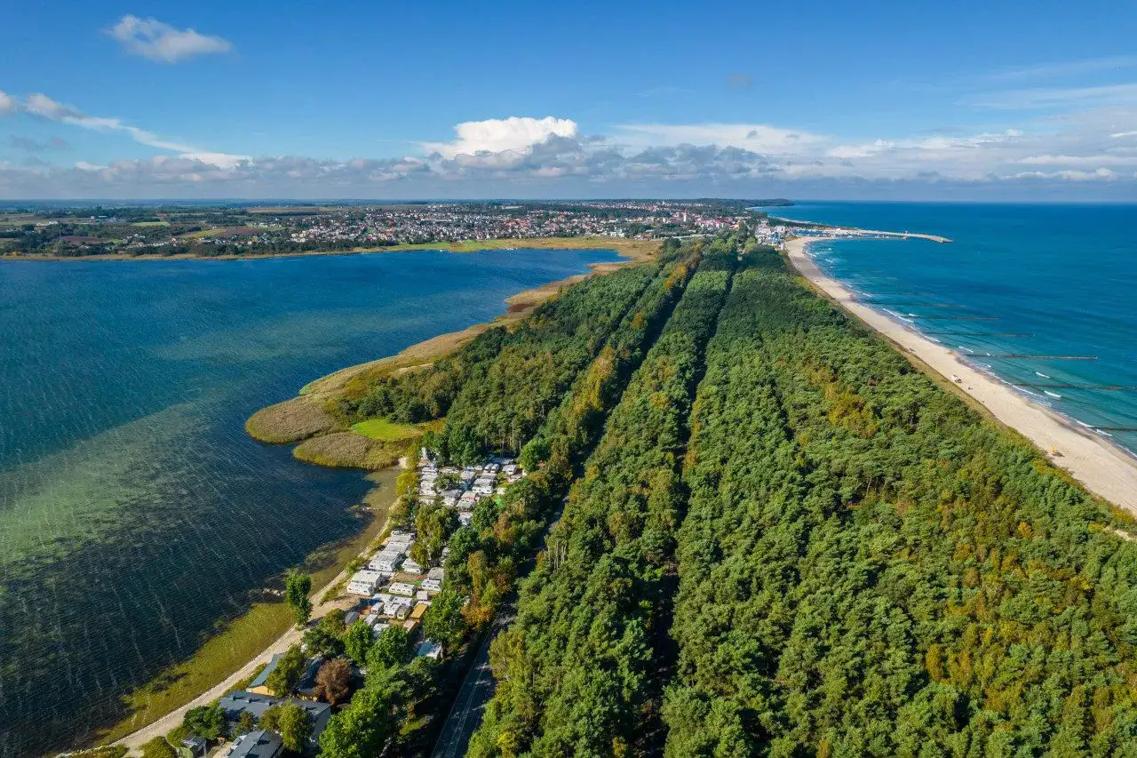 Półwysep Helski widziany z lotu ptaka: las sosnowy, plaża, morze i zatoka. Widać też miasteczko i kemping.