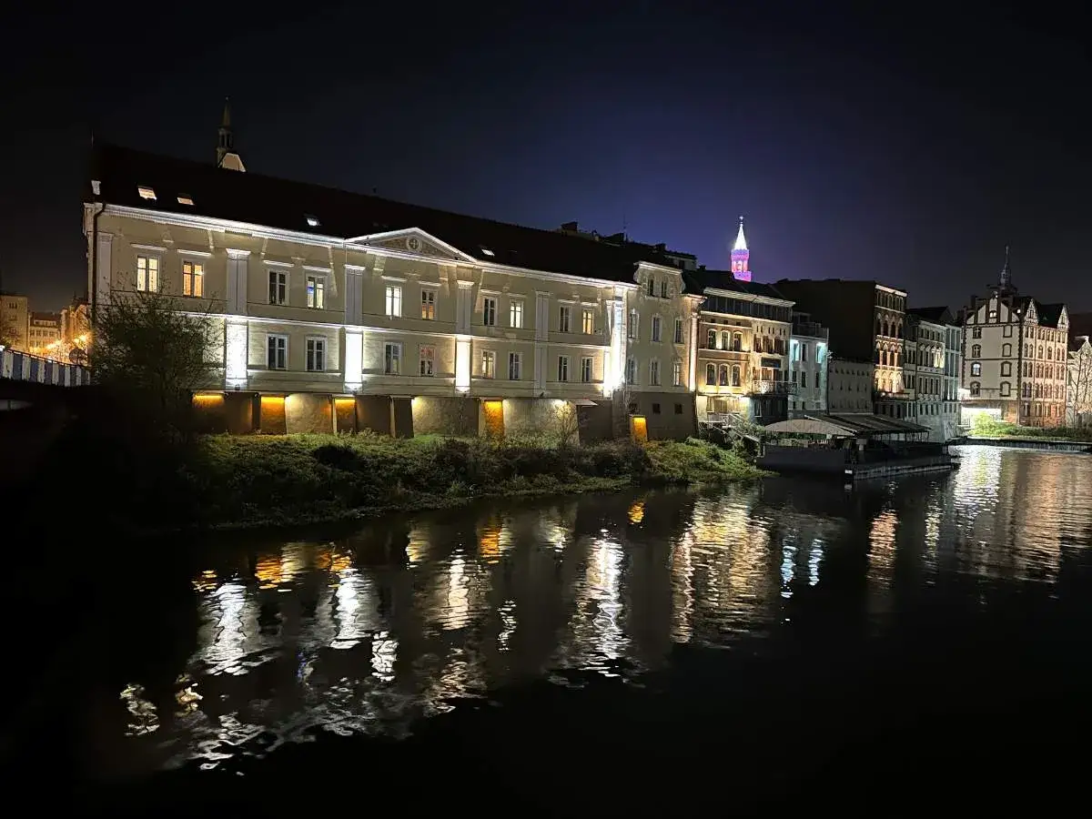 Nocna panorama miasta nad rzeką, z oświetlonymi kamienicami tworzącymi opolską wenecję.