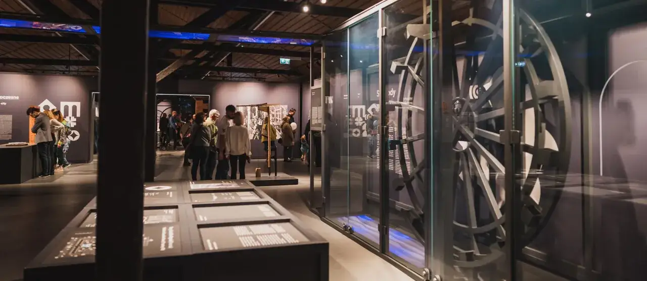 Wystawa w muzeum motoryzacji Kraków. Zwiedzający oglądają ekspozycję z elementami mechanicznymi i historycznymi.
