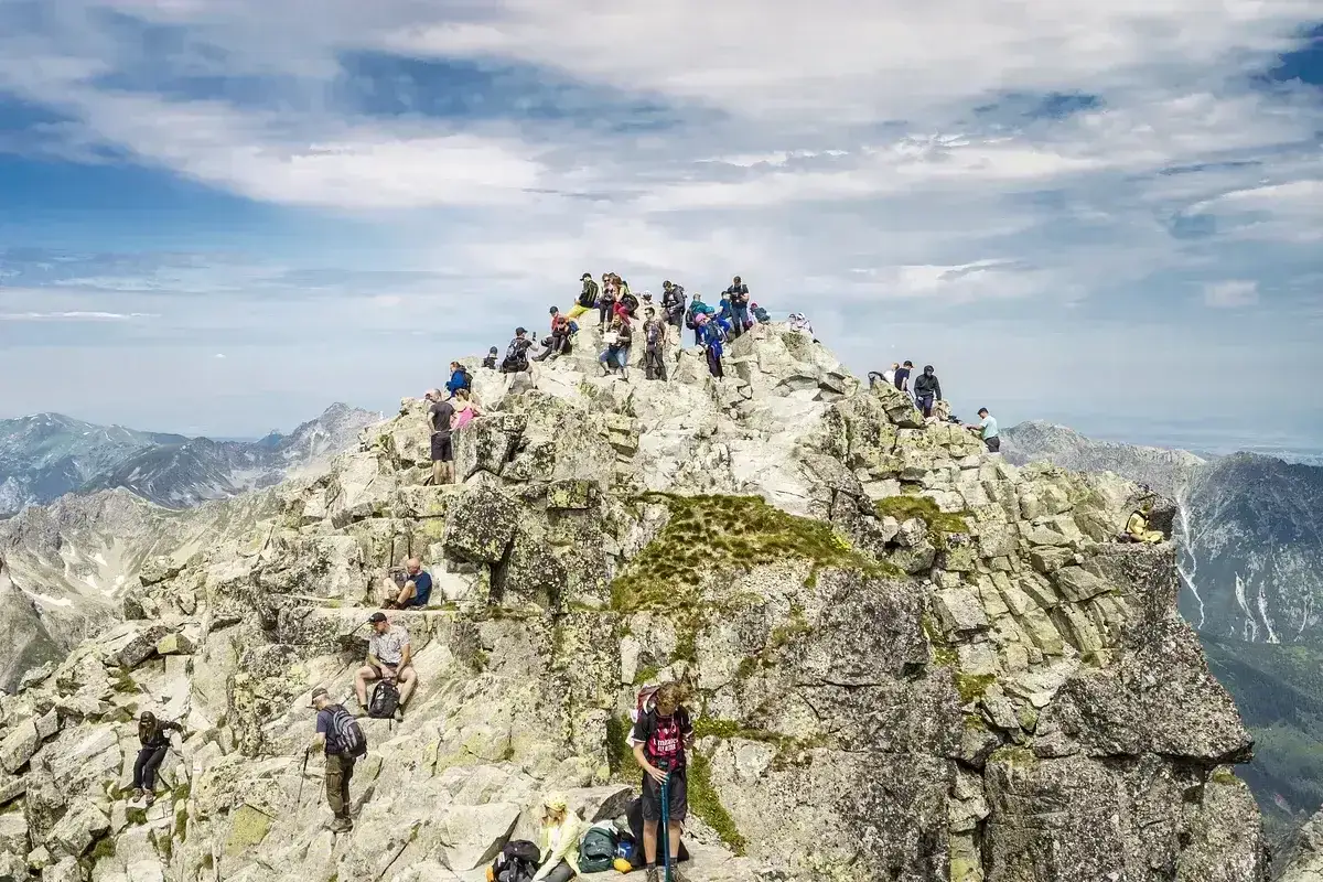 Tłum turystów na skalistym szczycie Rysów od strony polskiej. Widok na Tatry z góry.