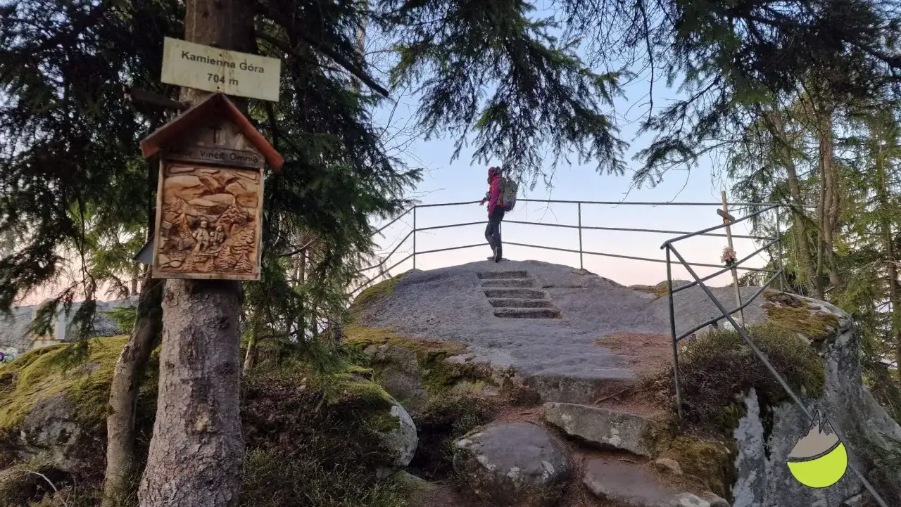 Widok na szczyt Kamienna G&oacute;ra (704 m). Turystka podziwia panoramę z platformy widokowej.